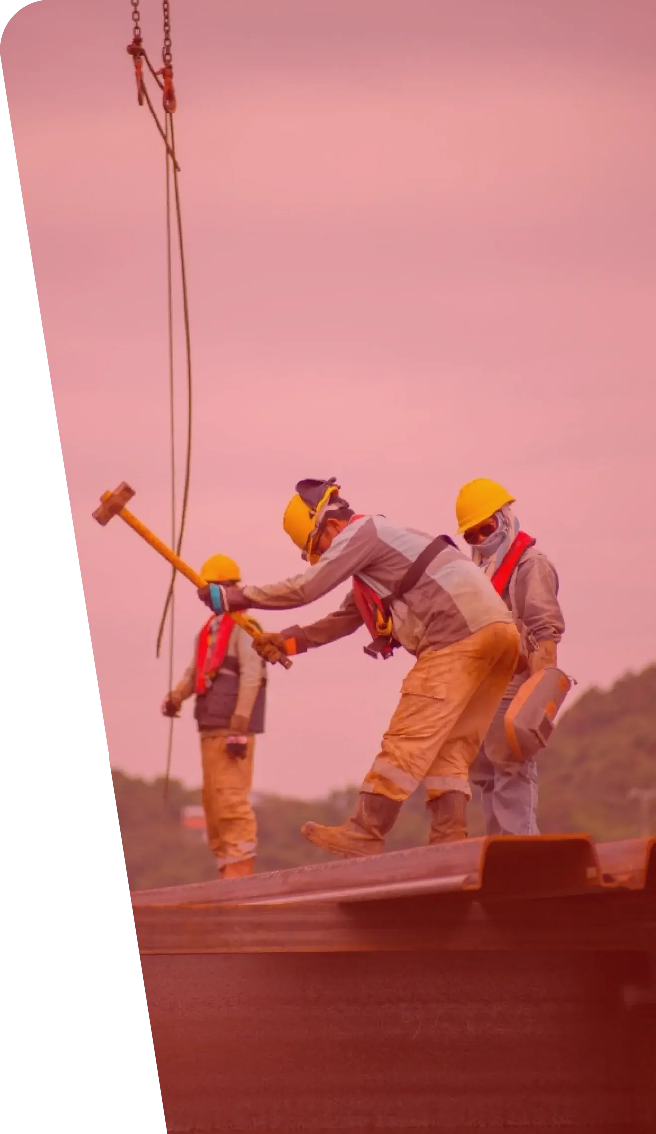 Three construction workers wearing yellow helmets and safety vests are diligently providing their services on a site. One worker is swinging a hammer, while the other two stand nearby. A crane with lifting cables looms in the background, all under an overcast sky.