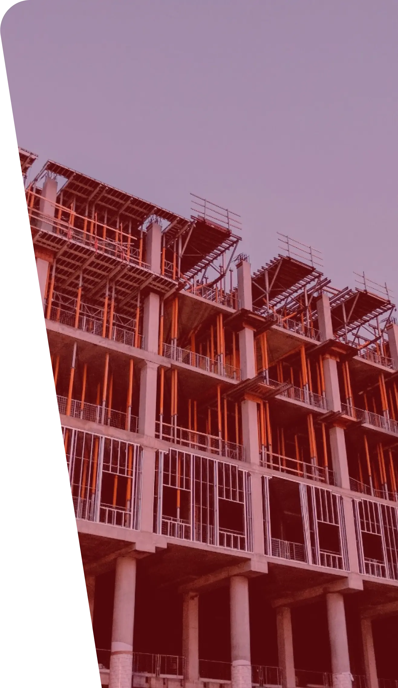 A partially constructed building with exposed beams and scaffolding. The structure has multiple floors, some of which are incomplete. The photograph, capturing a site bustling with construction services, has a reddish tint, and the left side is obscured by a dark triangular shape.