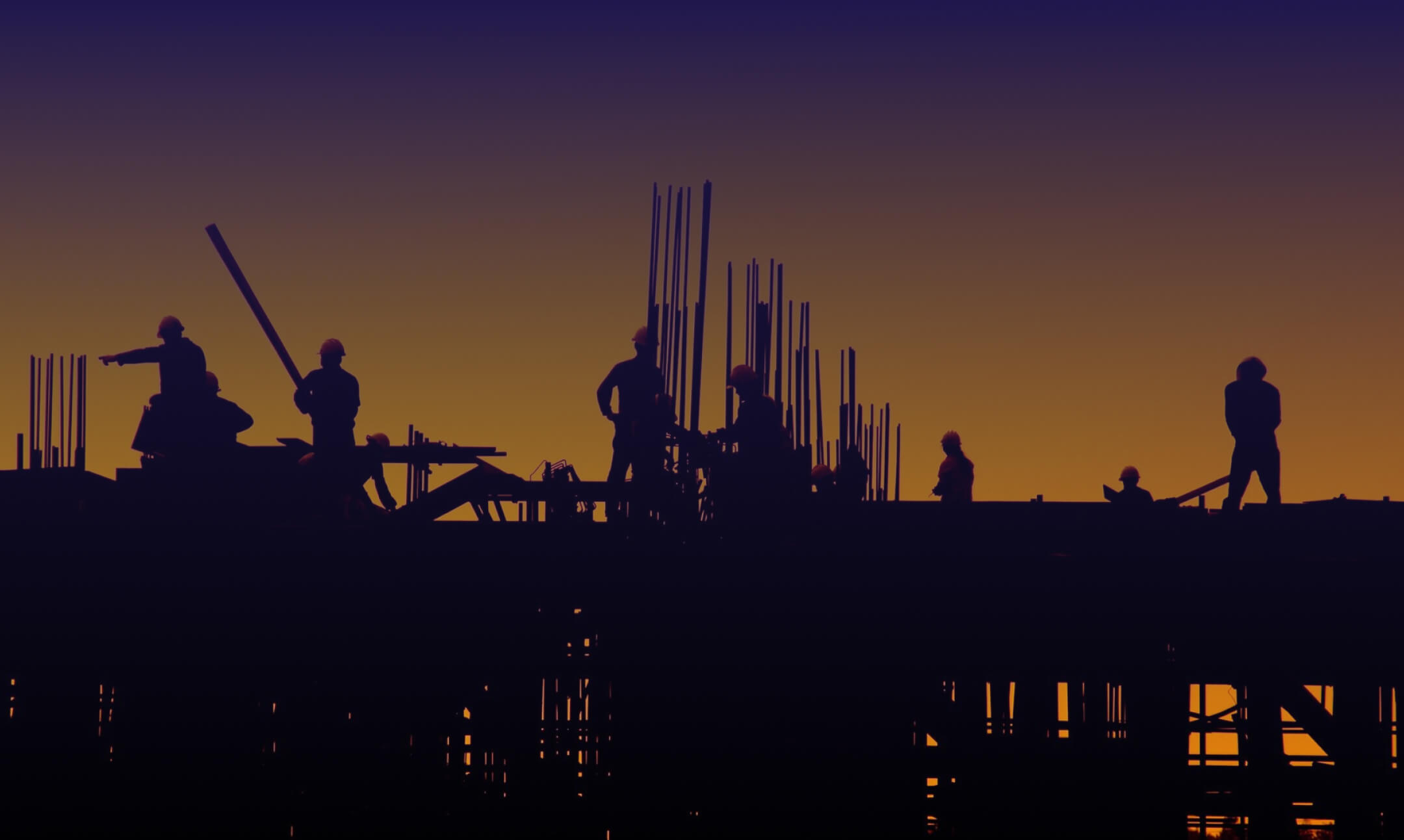 Silhouetted construction workers are seen at a building site during sunset, diligently providing essential services. The sky transitions from deep purple at the top to a warm orange near the horizon. Metal rods and framework are visible in the silhouetted structure.